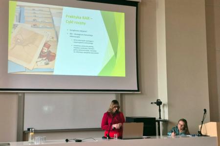 Ella Kok-Majewska w czasie wystąpienia; za stołem prezydialnym Marlena Jabłońska
